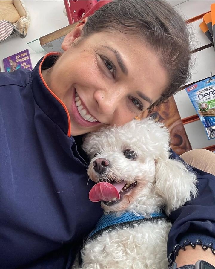 Dra. Sara Burrini abraçada com um poodle branco após a consulta