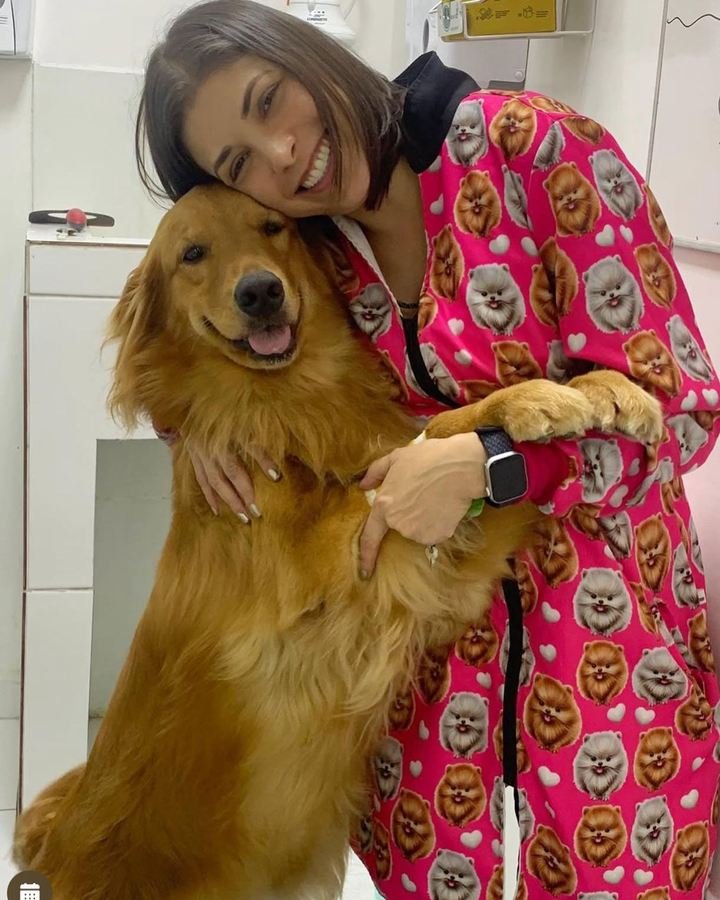 Dra. Sara Burrini abraçando um golden retriever durante o atendimento