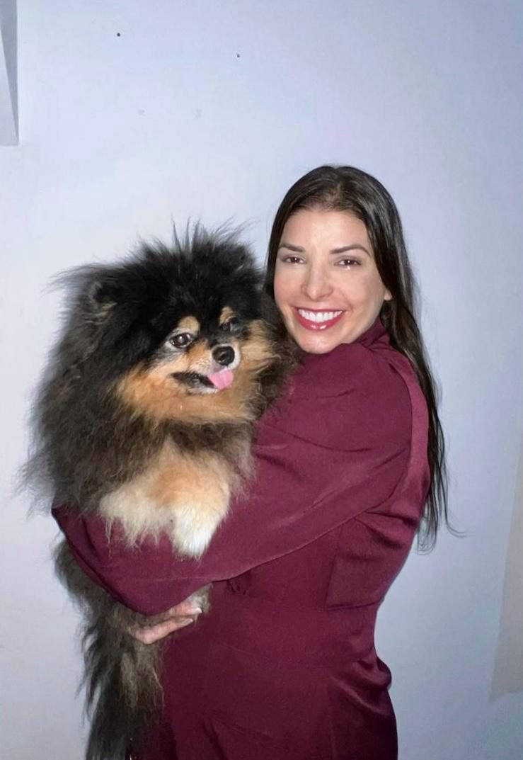 Dra. Sara Burrini segurando no colo um lulu da pomerânia preto